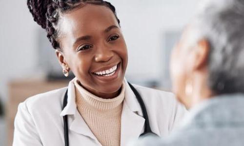 Women's health nurse practitioner smiling while speaking with female patient